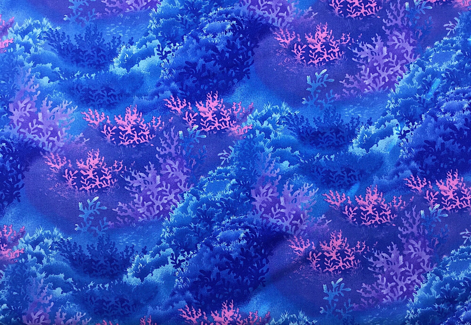 This fabric is called sea world and is covered in coral in shades of blue, pink and purples