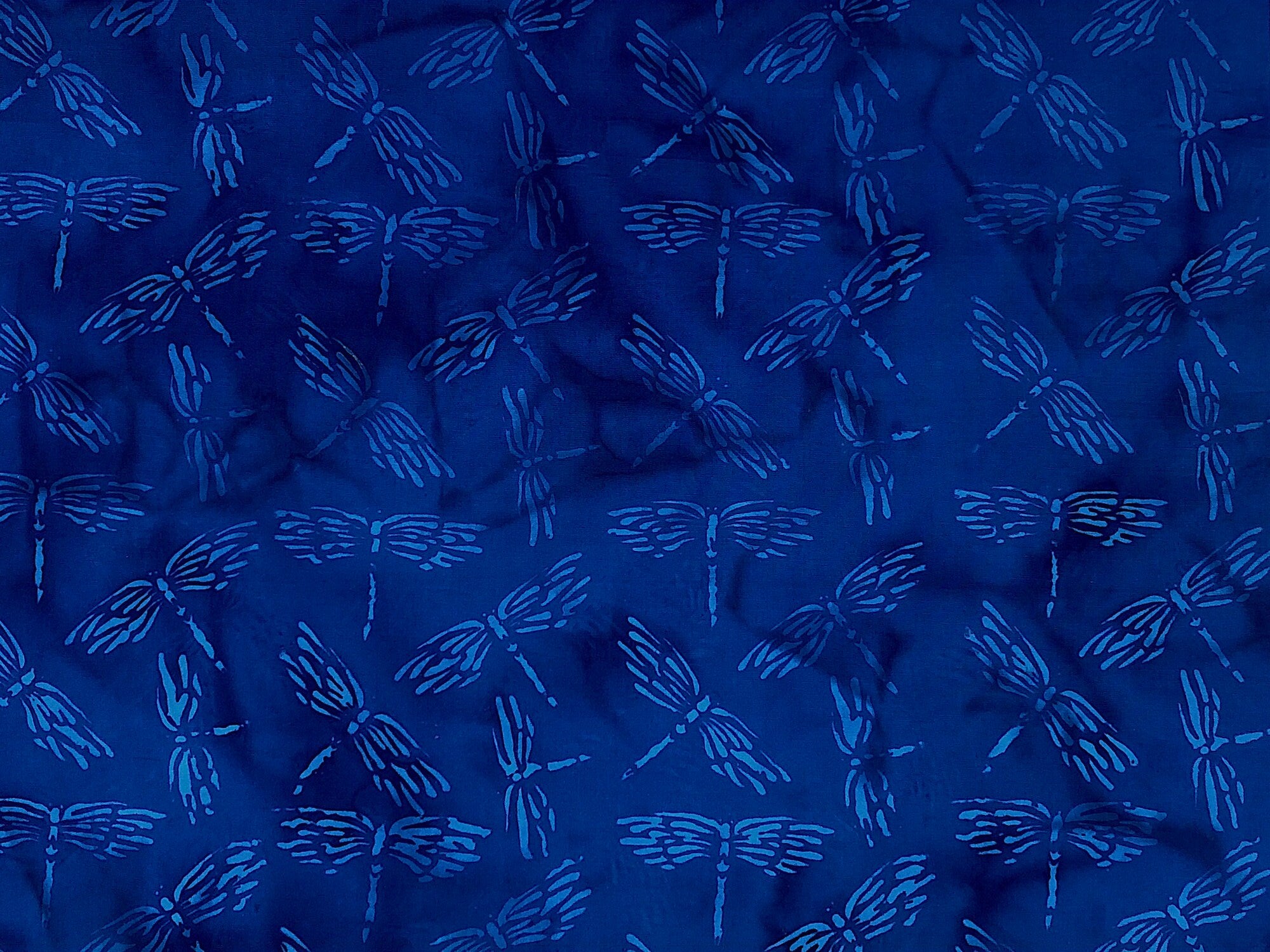 Blue batik fabric covered with dragonflies.