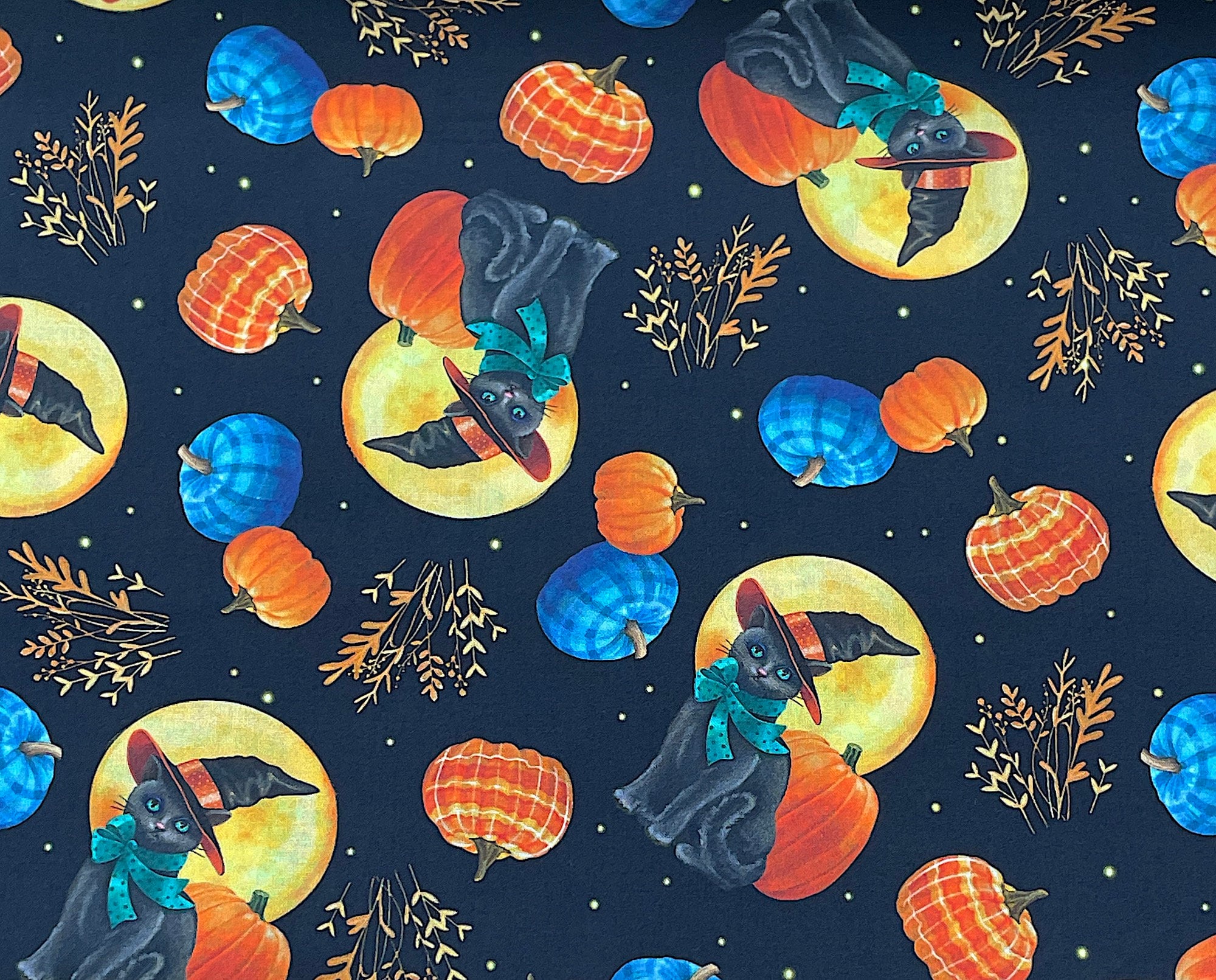This black fabric is covered with full moons, black cats, pumpkins and more. The cats have scarves and are wearing black hats.