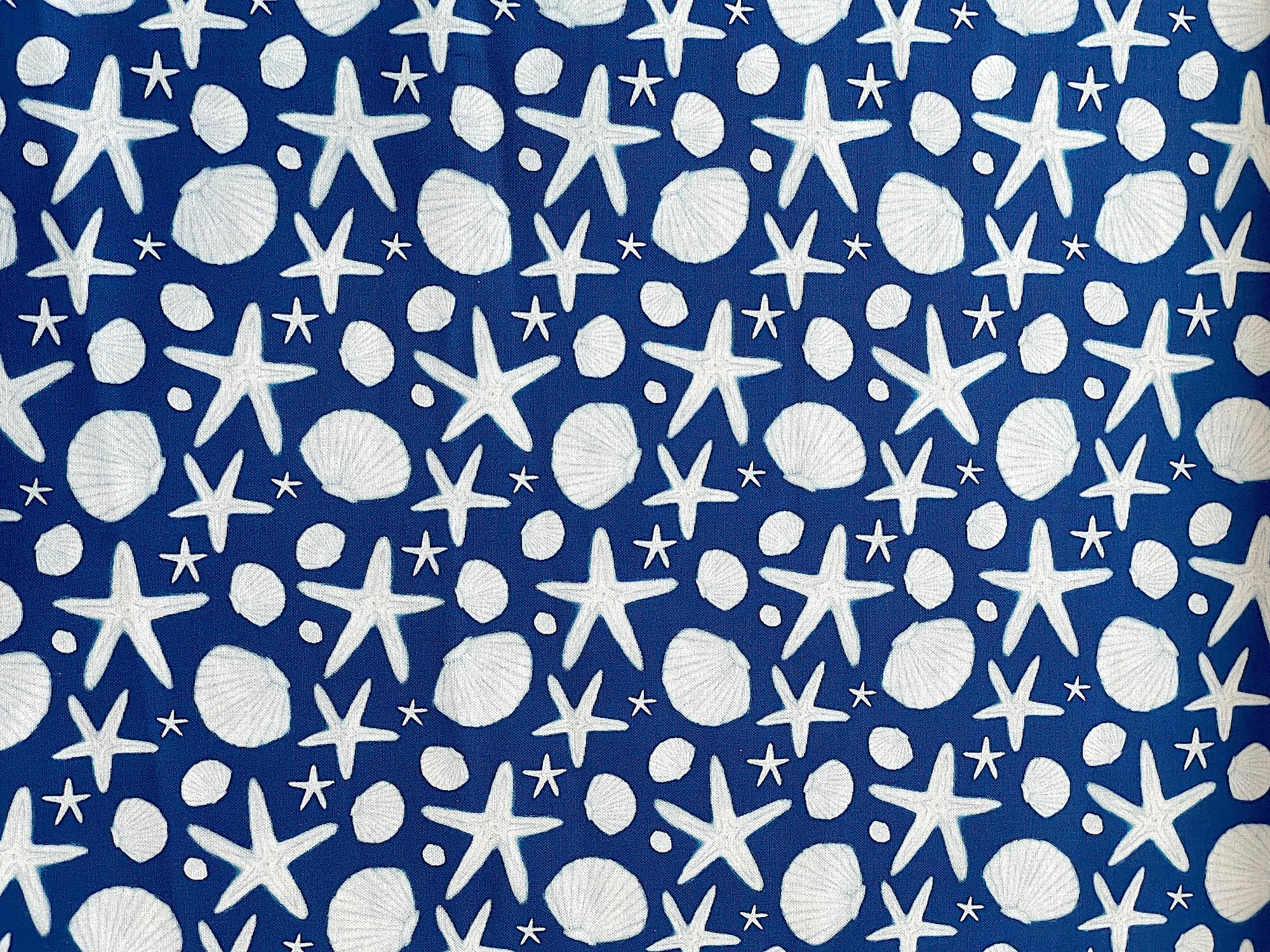 Cotton fabric covered with white sea shells and starfish.