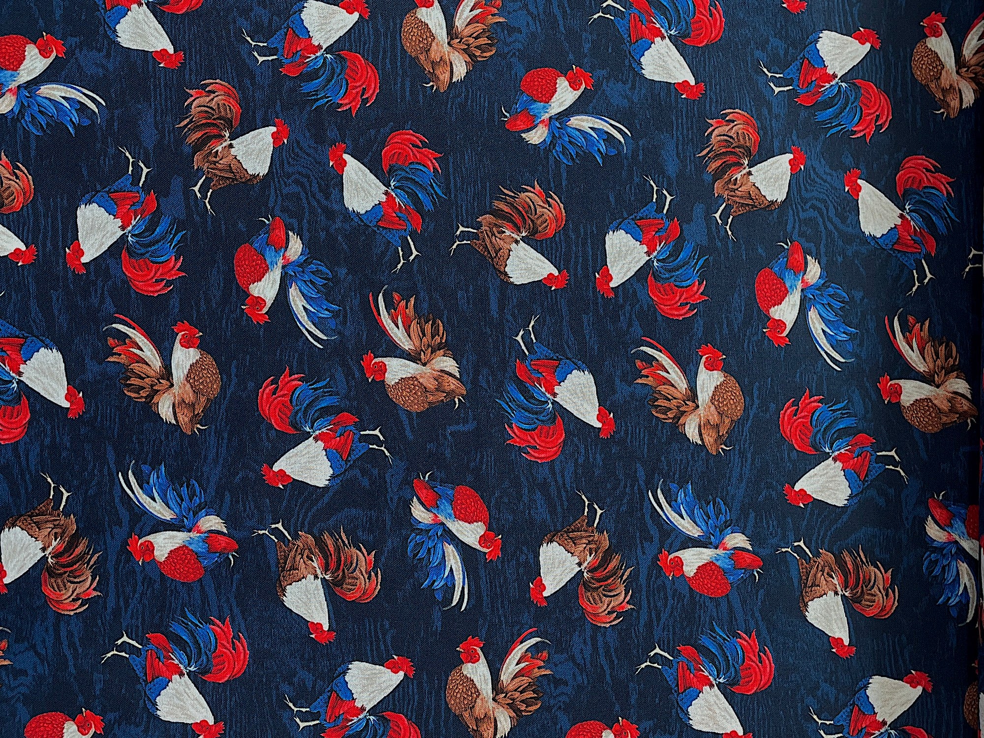 Cotton fabric covered with red, white, blue and brown roosters.