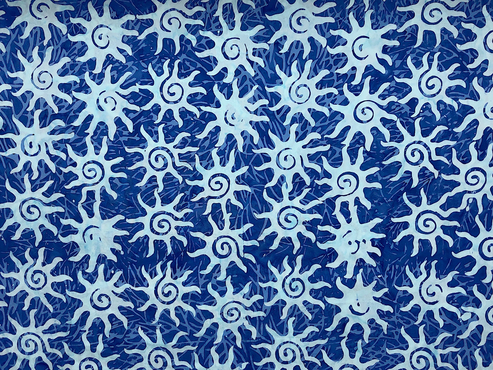 This blue Batik fabric is covered with light blue suns.