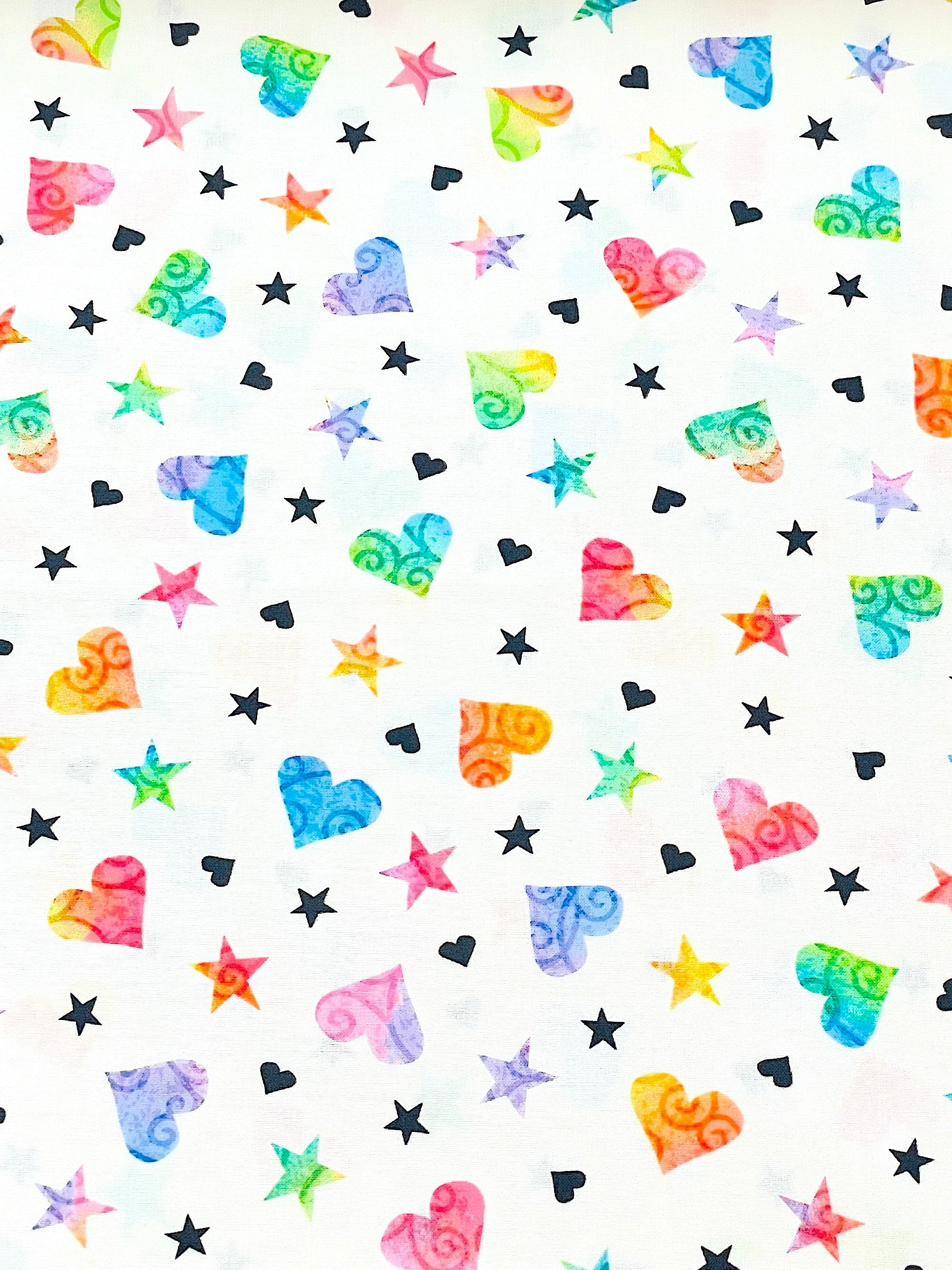 This fabric is called Be the change hearts and stars.  This white cotton fabric is covered with colorful stars and hearts.  There are purple, blue, red, yellow and green hearts and stars along with some black hearts and stars throughout the fabric.