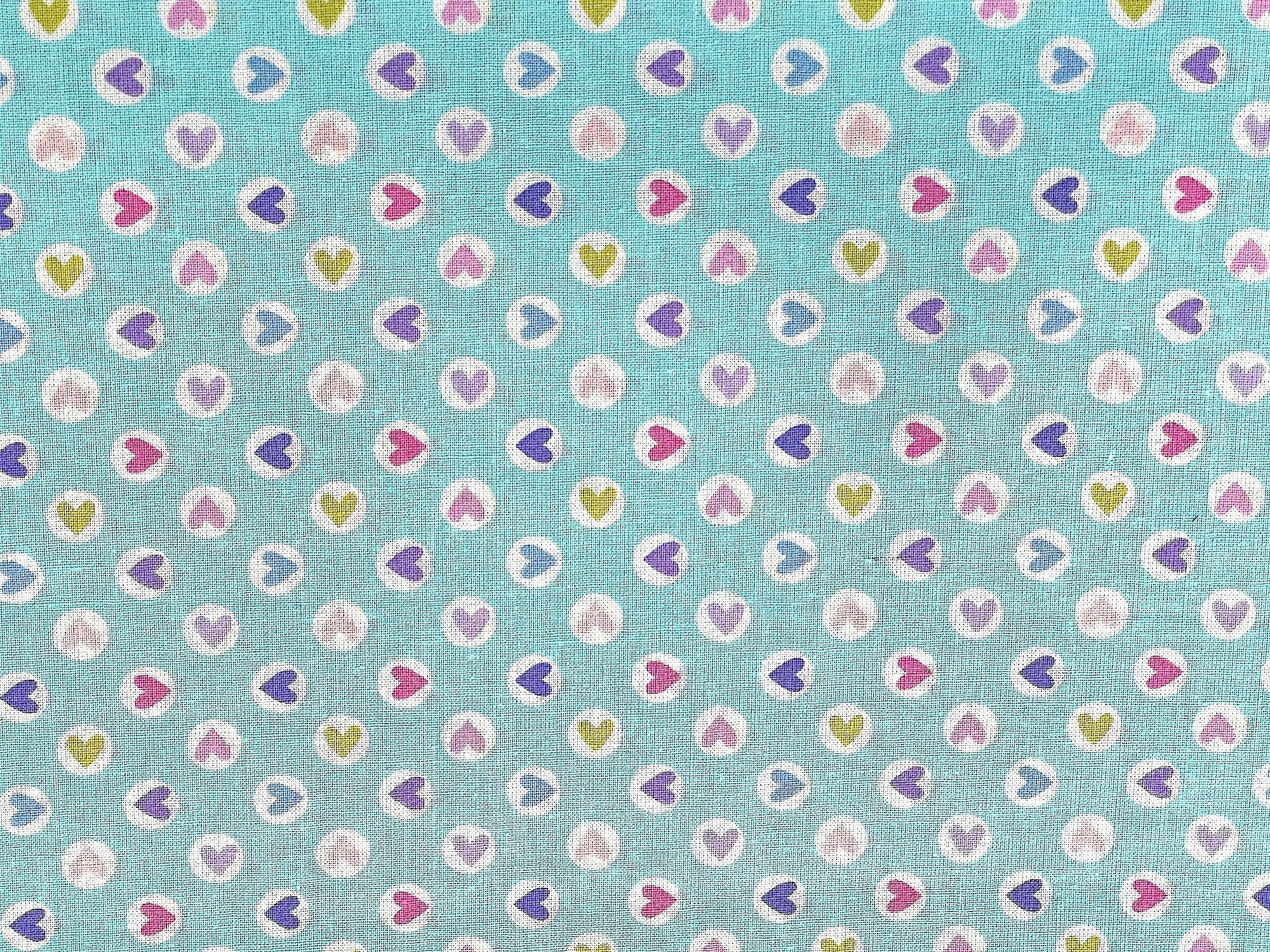 Turquoise colored fabric with different colored hearts within a white circle.