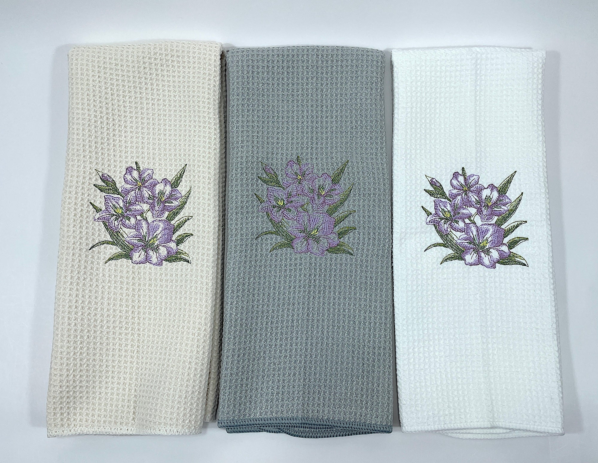 Three kitchen towels with floral embroidery on a white background