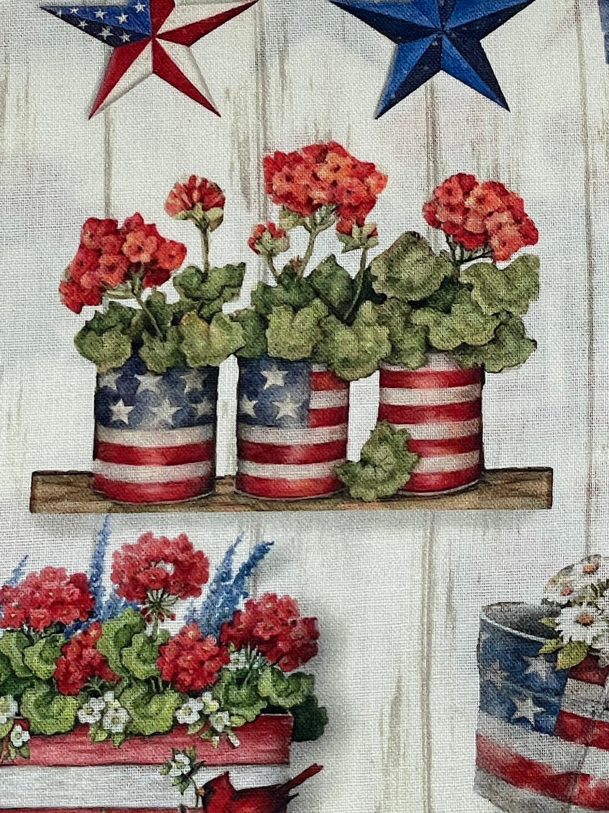 Close up of 4 cans of geraniums, the cans have USA flags on them.