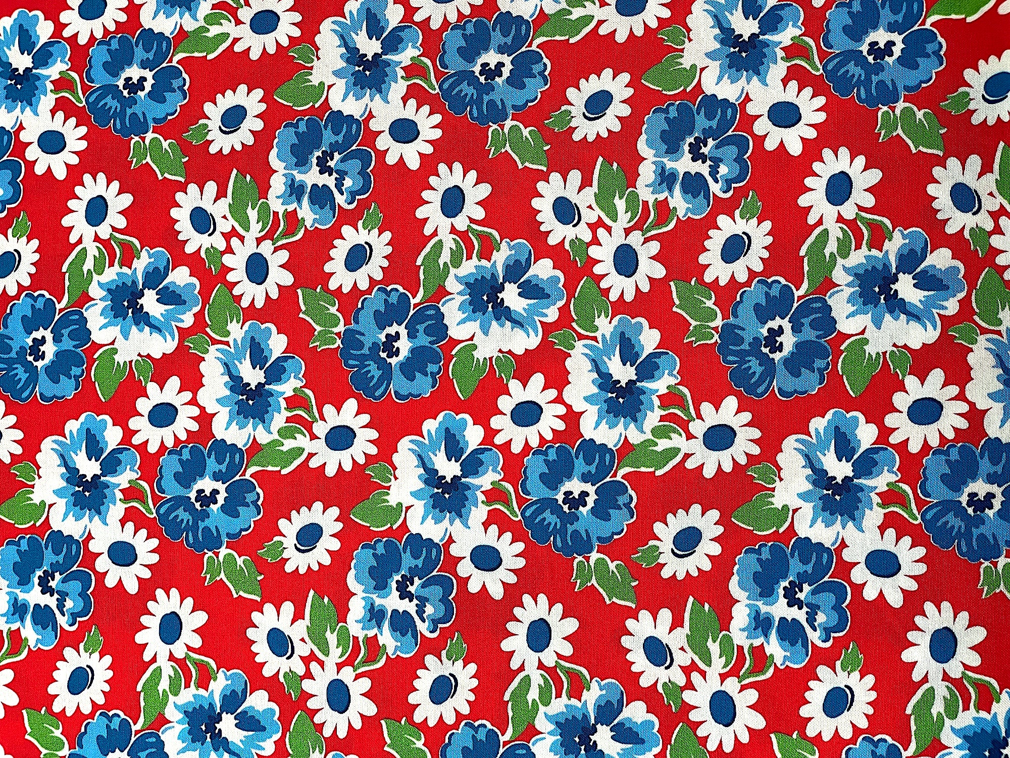 Red cotton fabric covered with blue and white flowers.