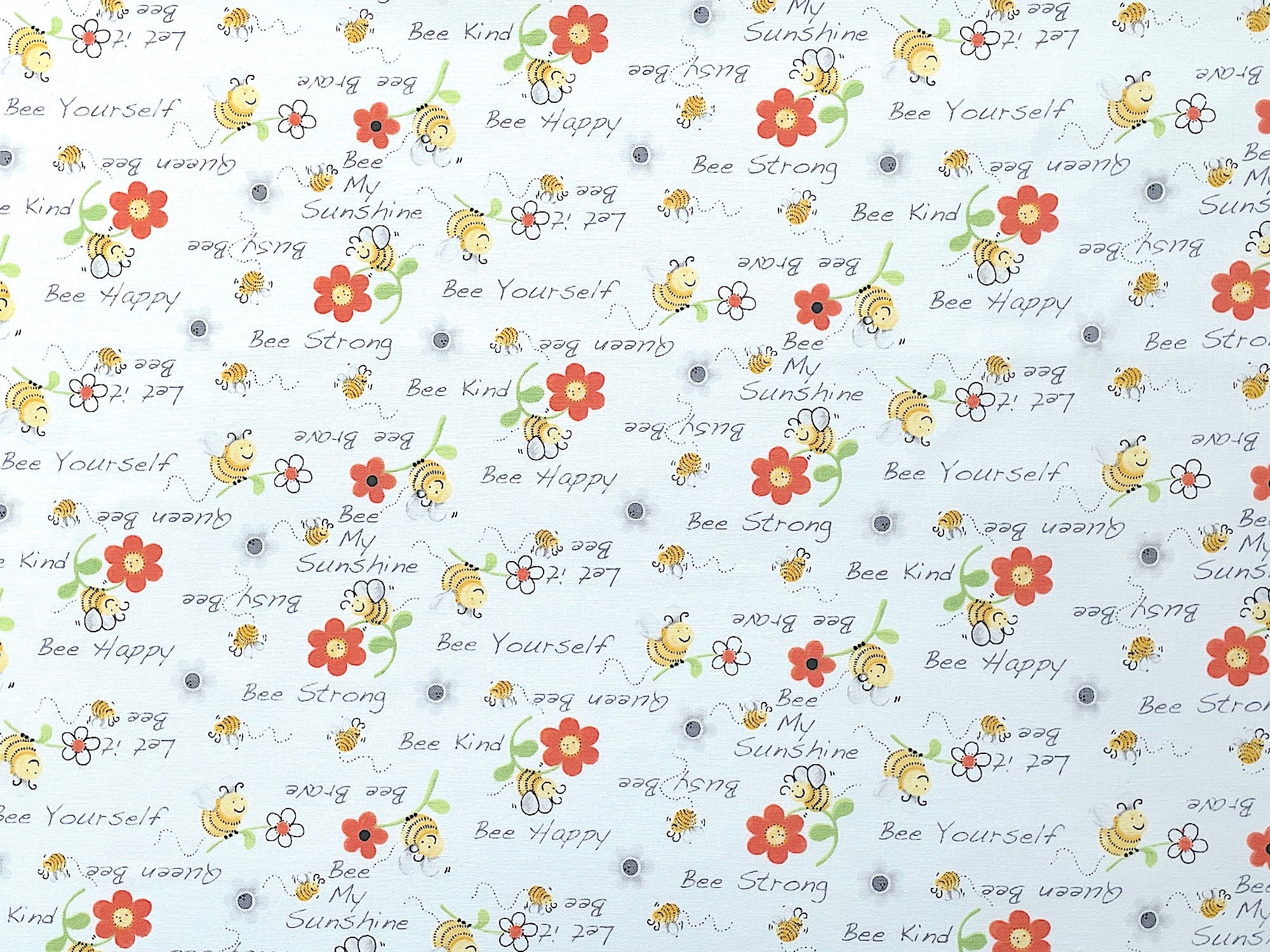 White cotton fabric covered with bees and sayings such as bee strong, bee kind, bee happy and more.