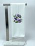White towel with purple floral design on a metal stand against a white background