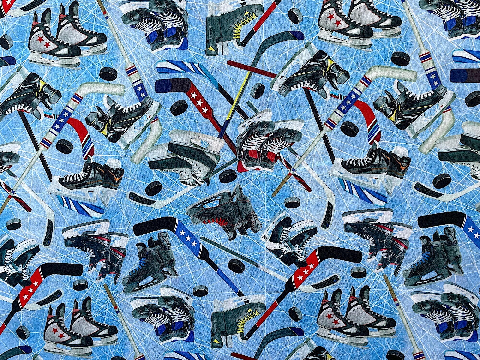 Blue fabric covered with ice skates, hockey sticks and pucks.