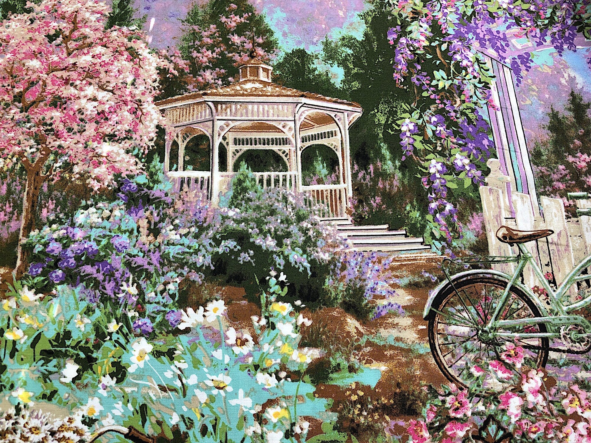 This fabric is called Flower Market Scenic and has a gazebo, bicycle and lots of flowers and trees.