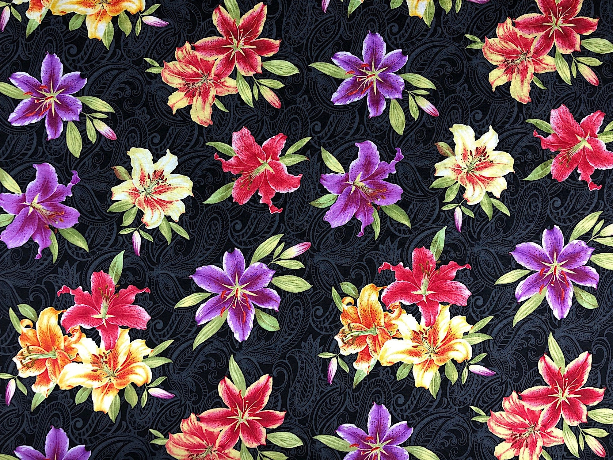 This fabric has yellow, purple and red lilies on a black background
