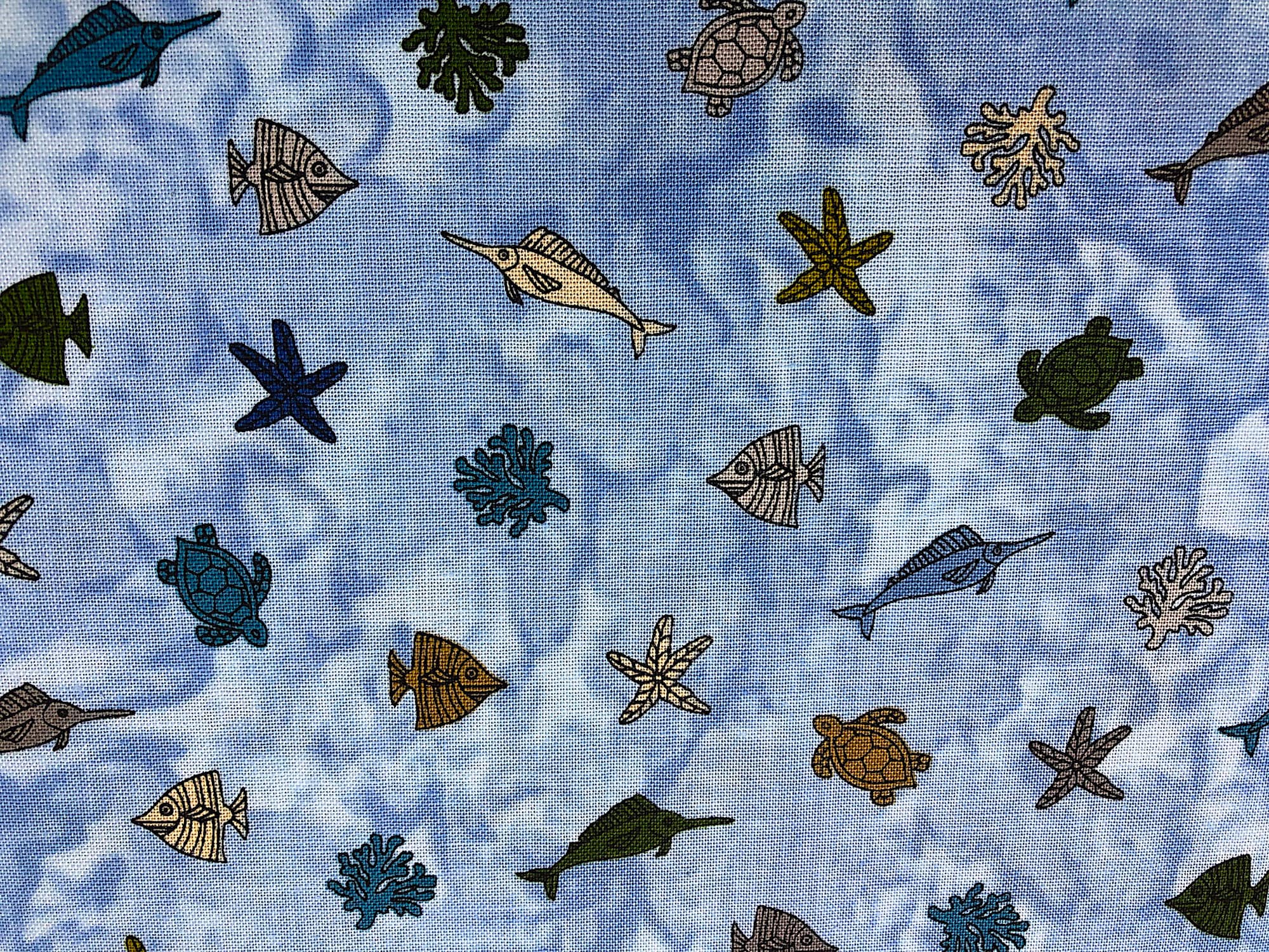 This fabric is part of the Turtle Bay collection and has small turtles, coral and starfish on a blue background.