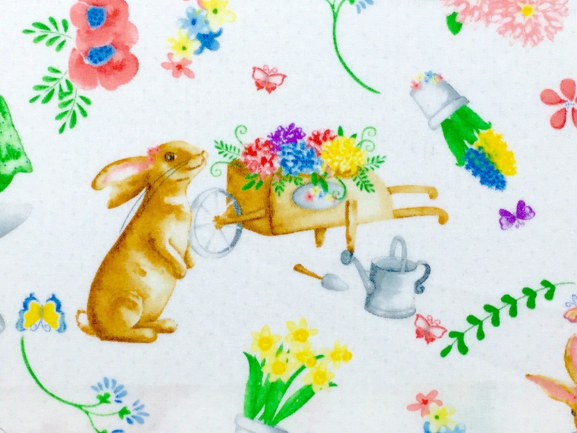 Close up of bunny, daffodils, watering can and shovels.