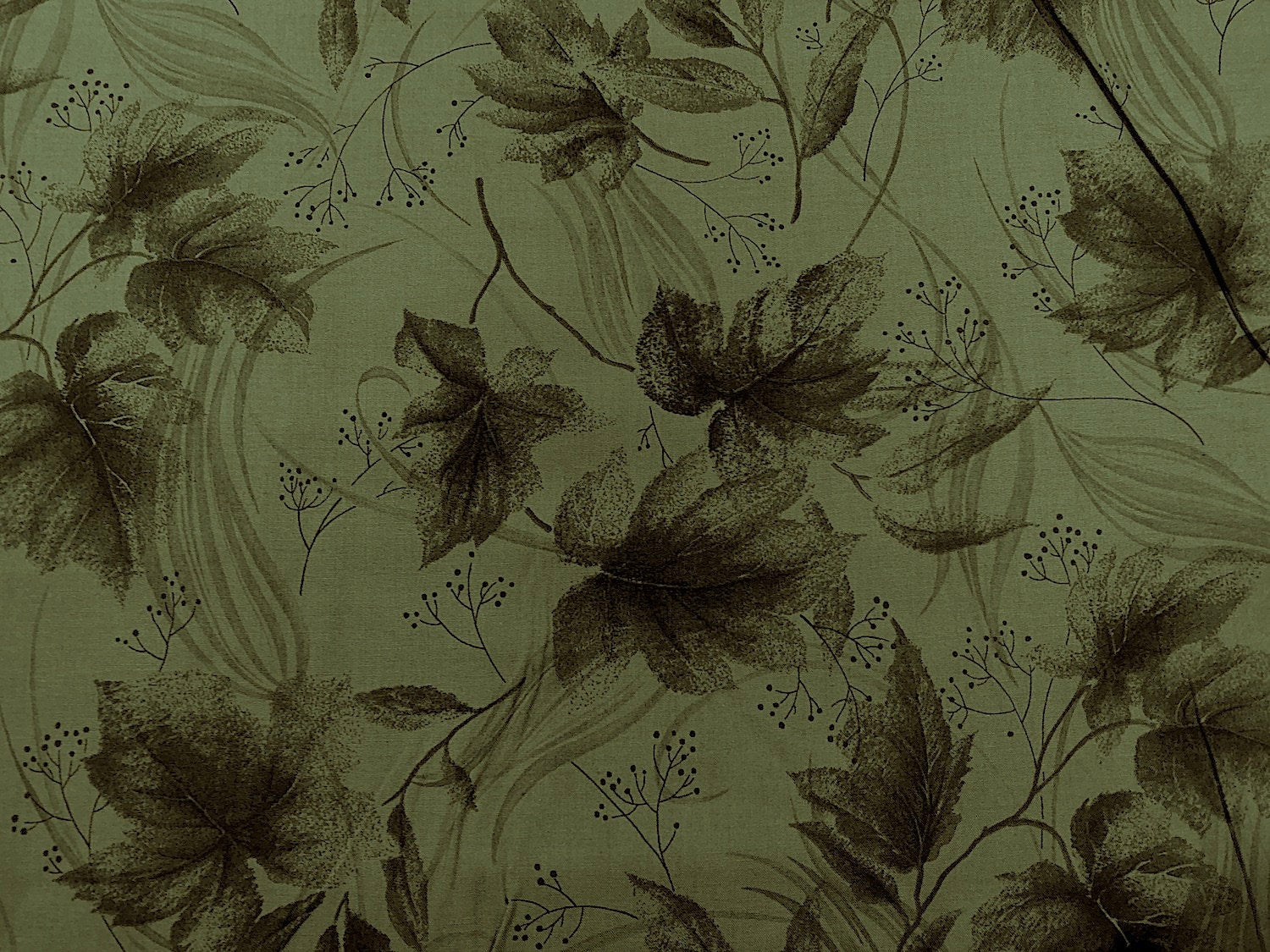 Green cotton fabric covered with leaves.