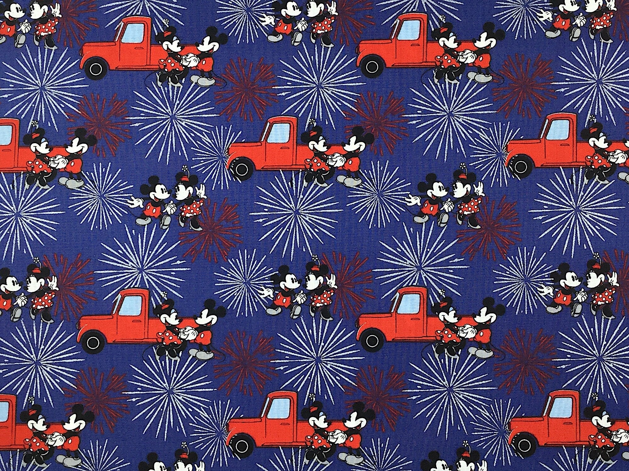 Blue cotton fabric covered with Mickey and Minnie Mouse, red trucks and fireworks.