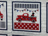 This panel fabric is covered with red trucks and black dogs. Each truck is in a different position on the fabric. Each panel has 15 squares with trucks and is approximately 25" wide.