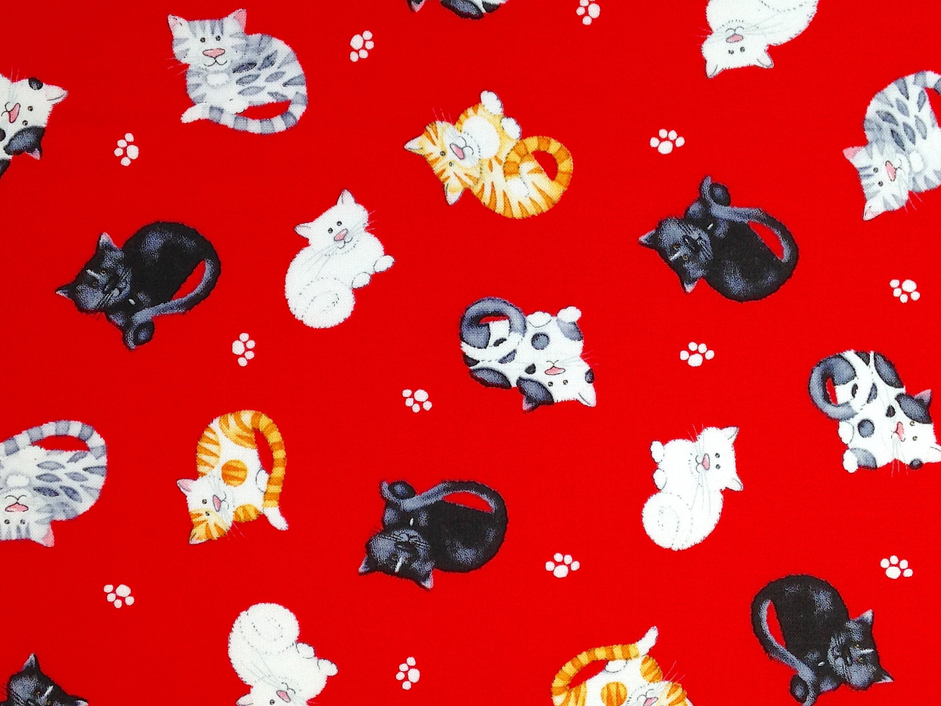 Cats and paw prints scattered on a red background. The cats are arranged in a random fashion on the fabric.