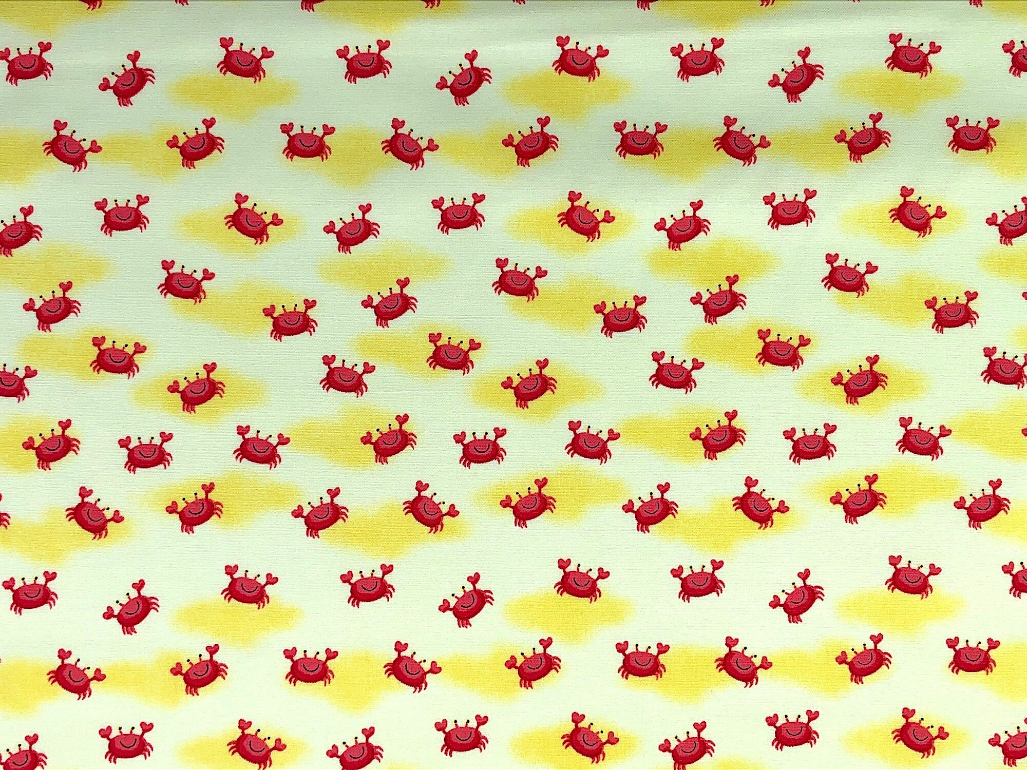 This yellow fabric is covered with crabs that have the claws raised in the air.