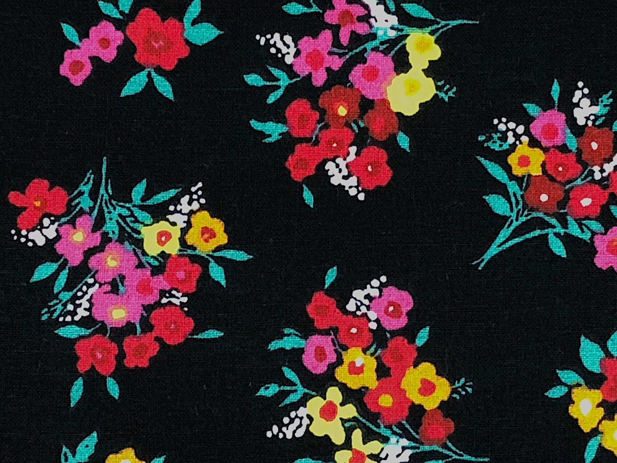 Close up of black cotton fabric covered with bouquets of flowers.