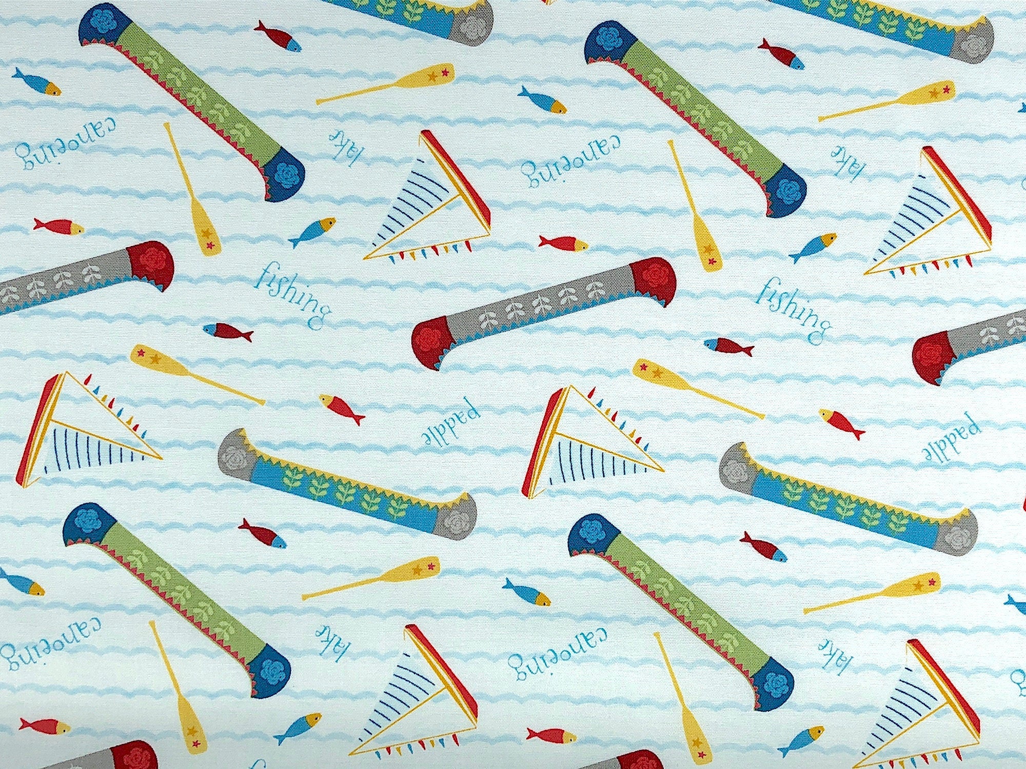 This fabric is called Let's go Glamping and is covered with canoes, oars, sail boats, and fish. There are rows of waves across the fabric. Lake and canoeing are printing throughout the fabric.