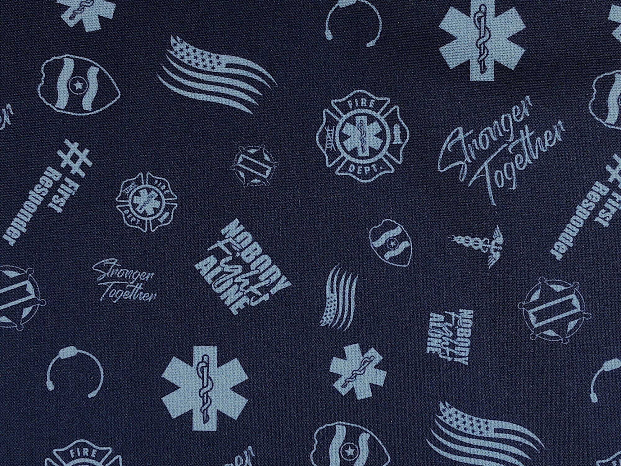 Blue cotton fabric covered with first responder insignias'.