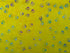 This yellow batik fabric is covered with shades of blue, green, pink and red paw prints