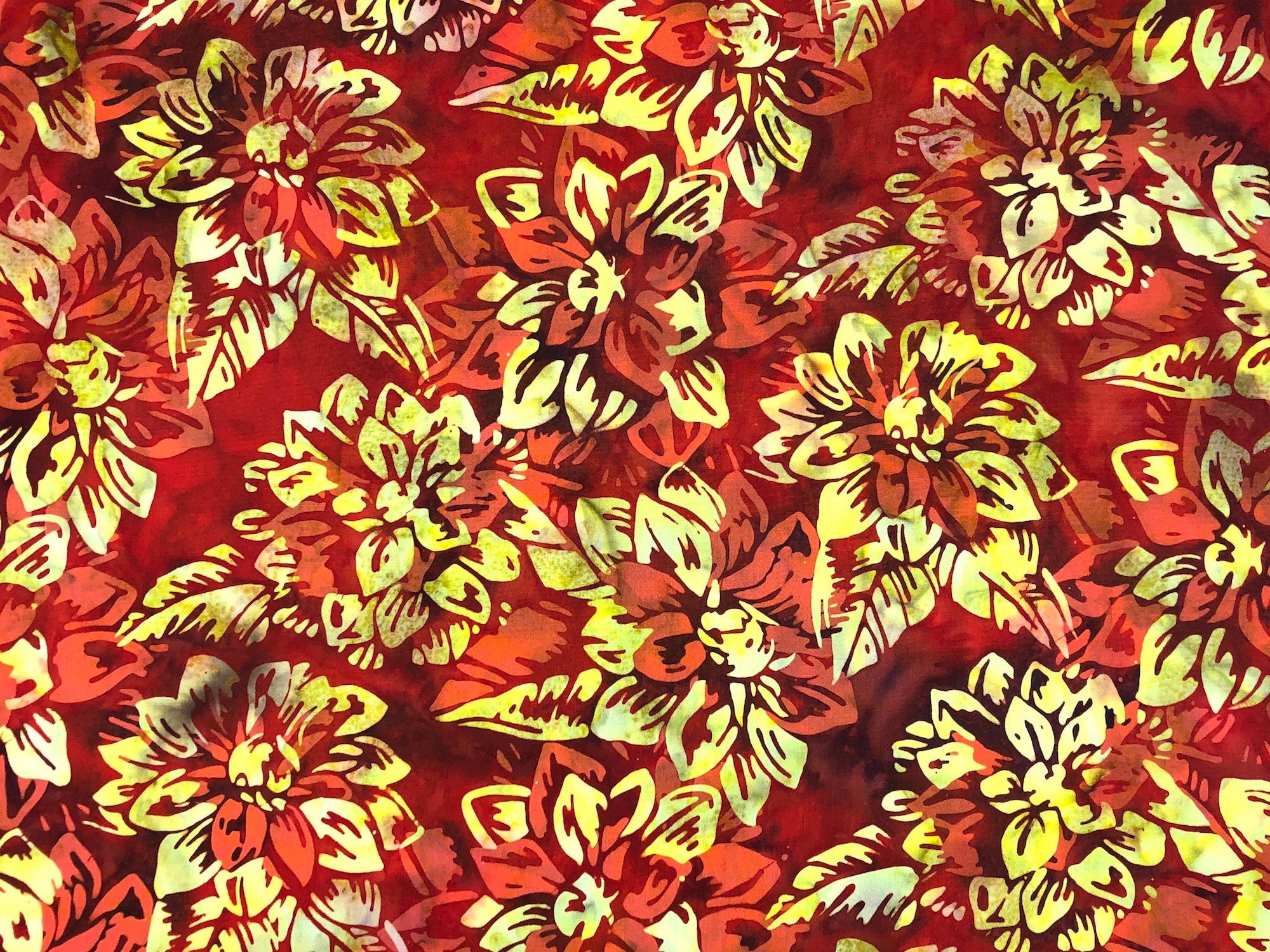 This batik fabric is covered with orange and yellow flowers. The background has several shades of brown and red.