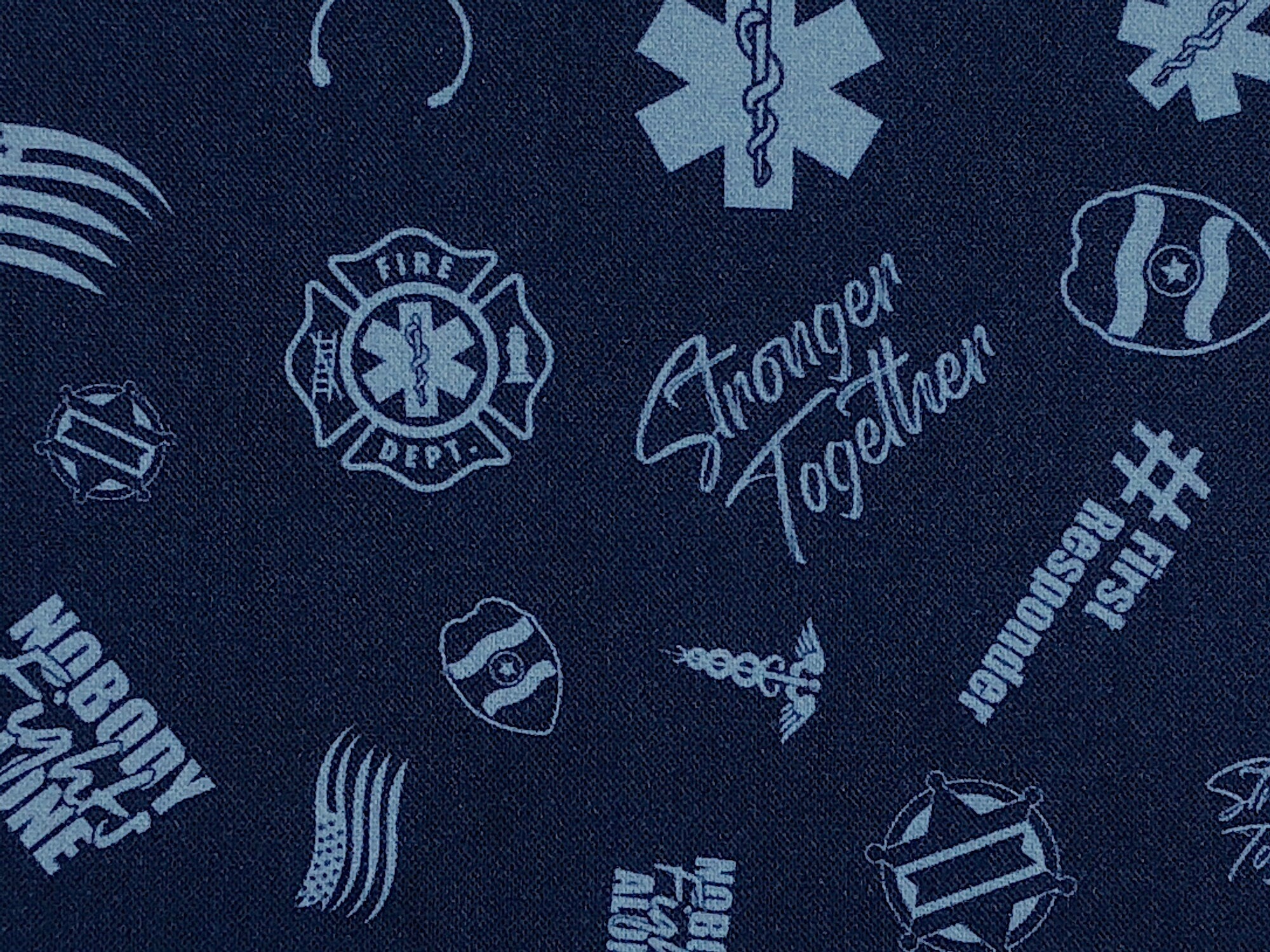 Blue cotton fabric covered with first responder insignias'.