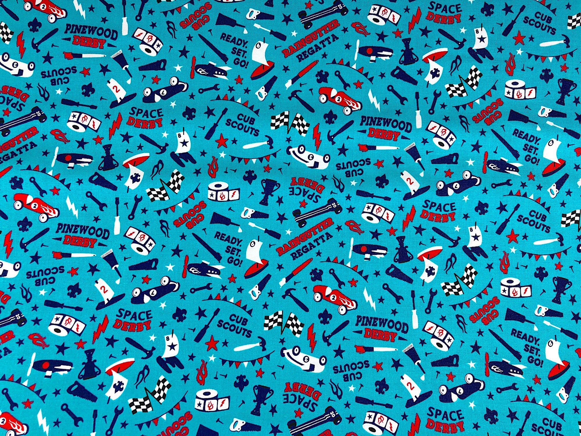 This fabric is called Cub Scouts Derby teal and is covered with hammers, saws, wrenches, paint brushes, cars and flags. Bub Scouts, Ready Set Go and Space Derby are just a few of the words printed on the teal fabric.