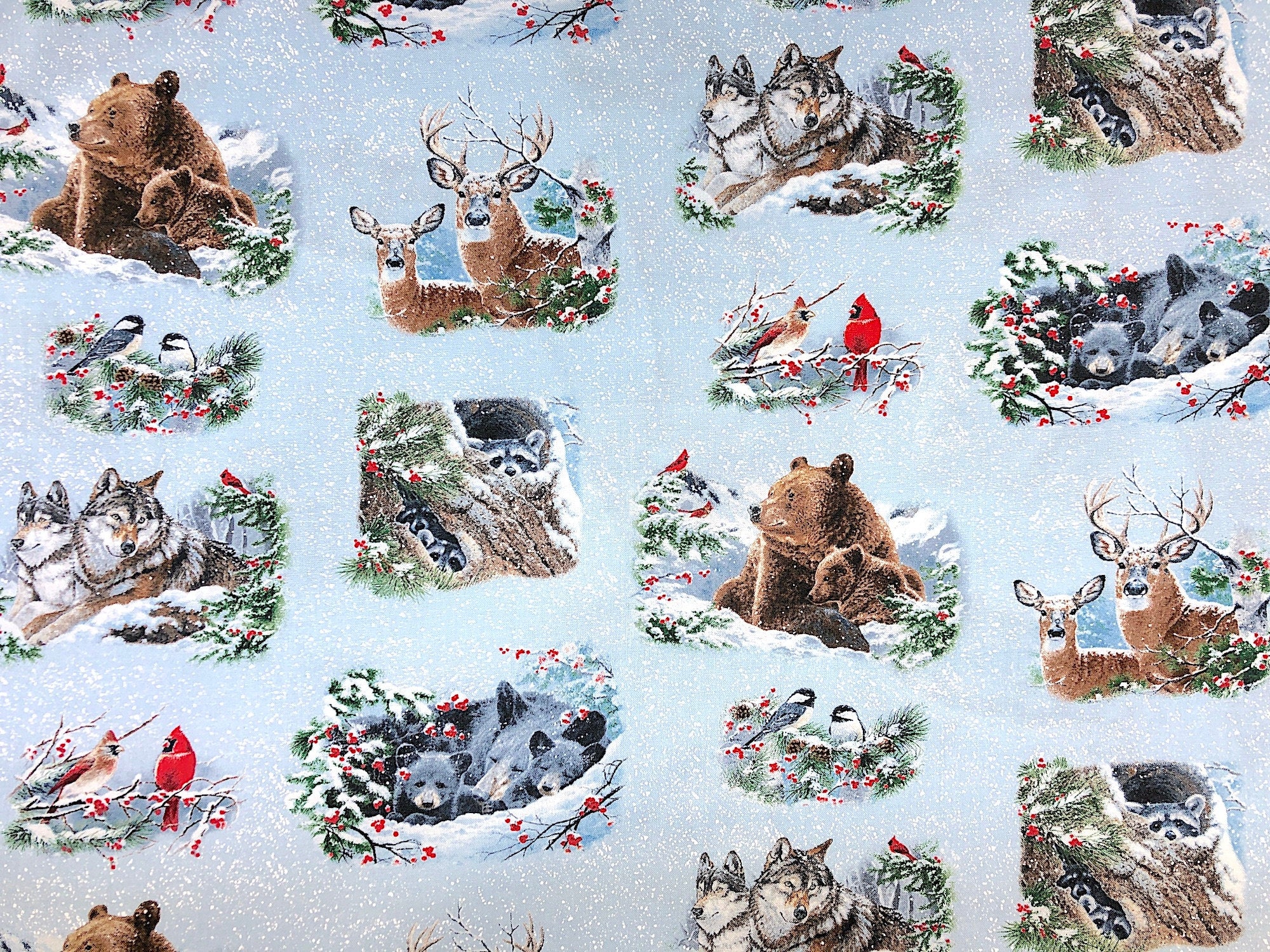 This fabric is called Winter Companions and is covered in bears, deer, raccoon, and birds. There is snow falling all over the light blue background.