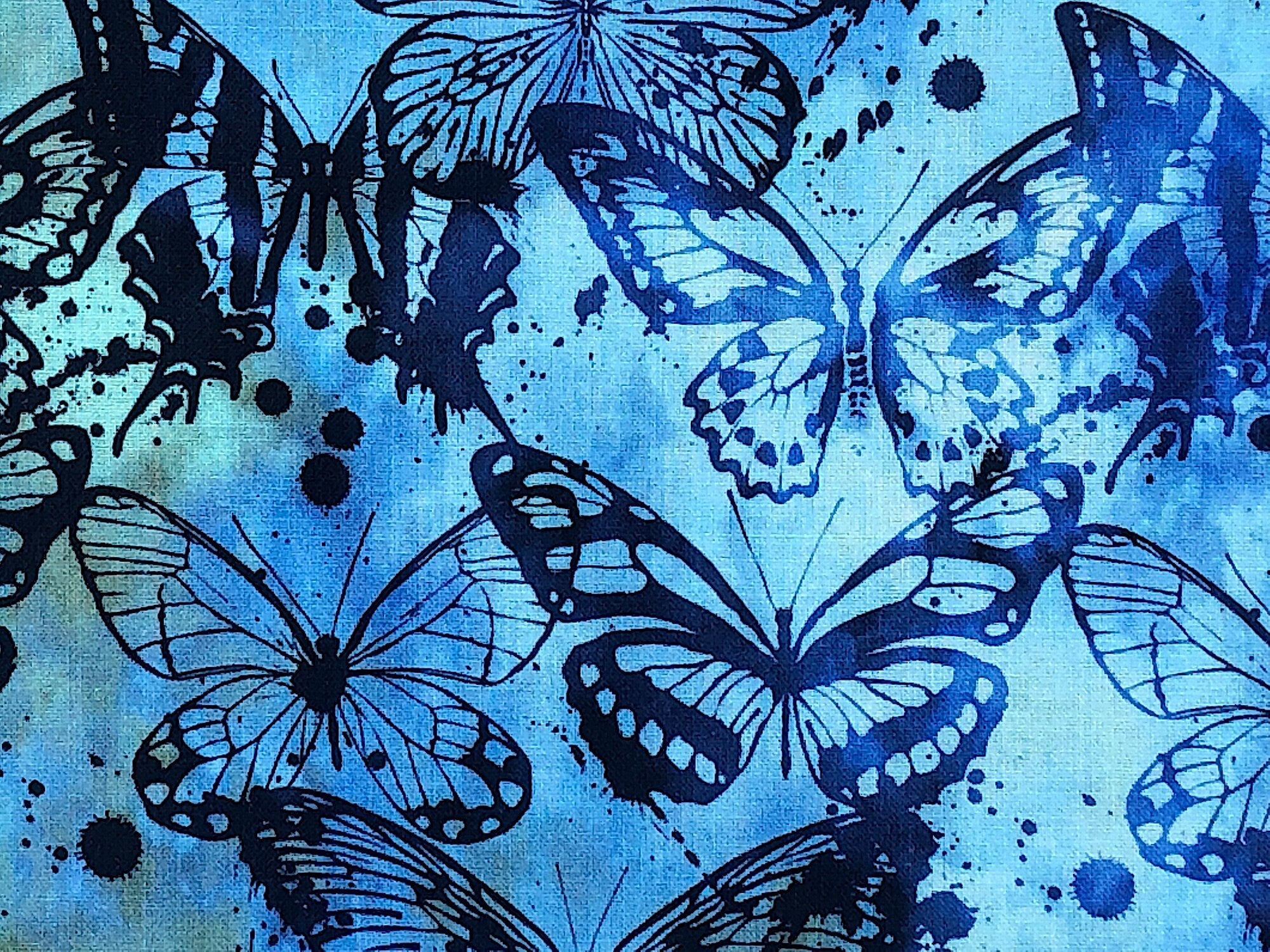 Close up of blue batik fabric covered with dark blue butterflies.