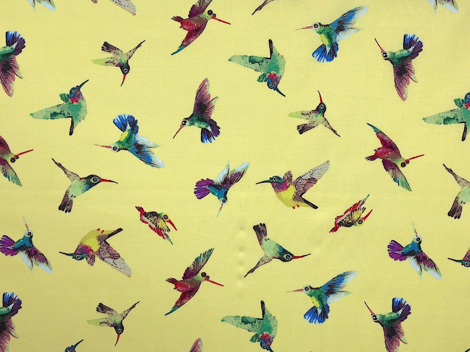 This fabric is part of the Flower Talk collection and is covered with colorful hummingbirds. The yellow background is covered with hummingbirds that are shades of blue, green, yellow, red and purple