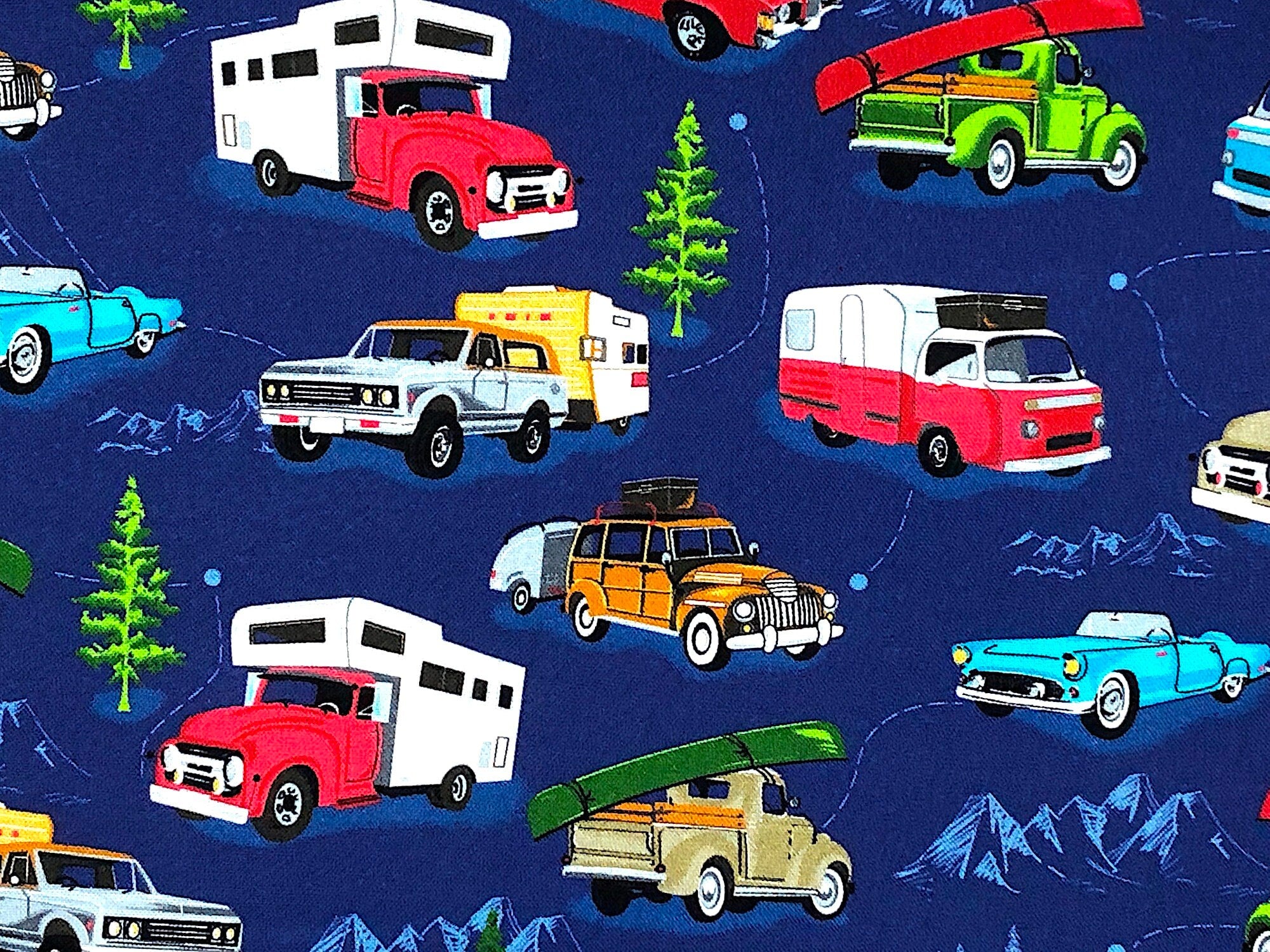 Close up of a truck pulling a travel trailer, cards, trees and more.