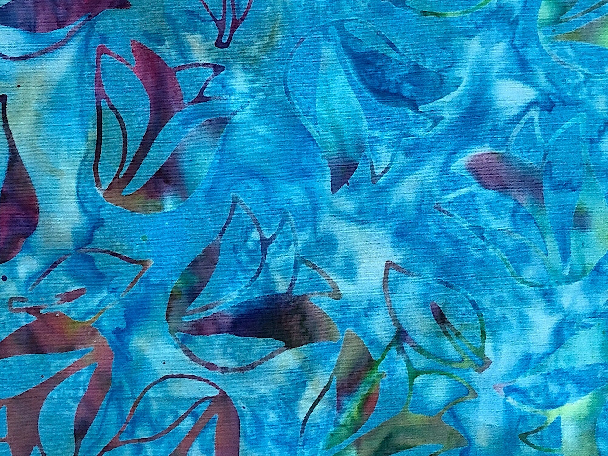This batik fabric is covered with tulips. The tulips are shades of blue, green, yellow, red and orange.