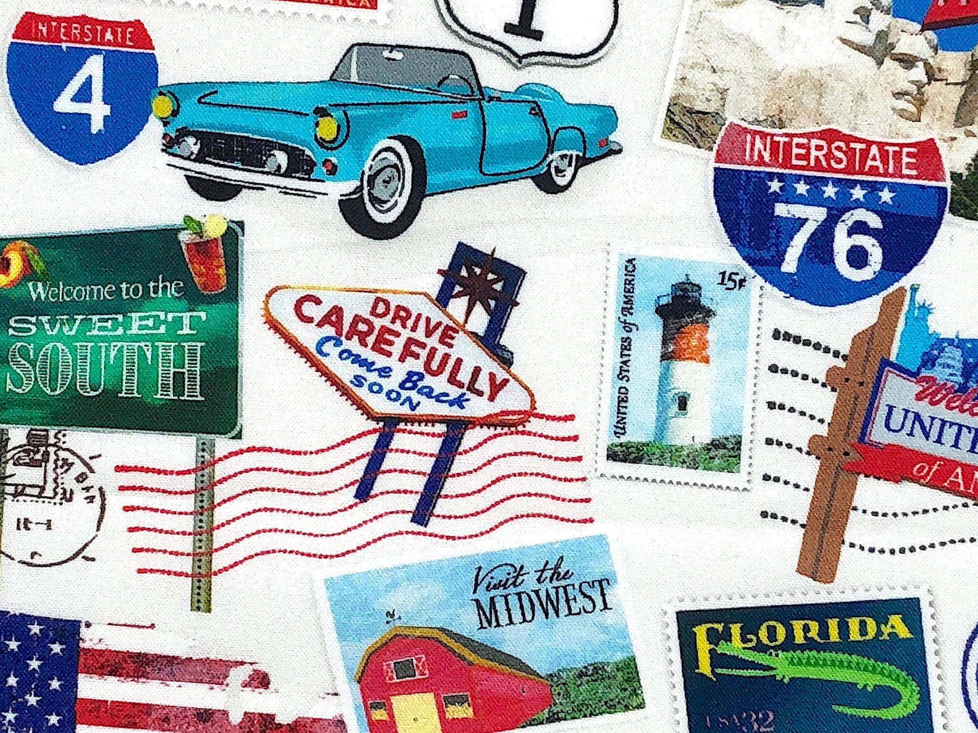 Close up of a blue car, stamps and a welcome to the sweet south sign.