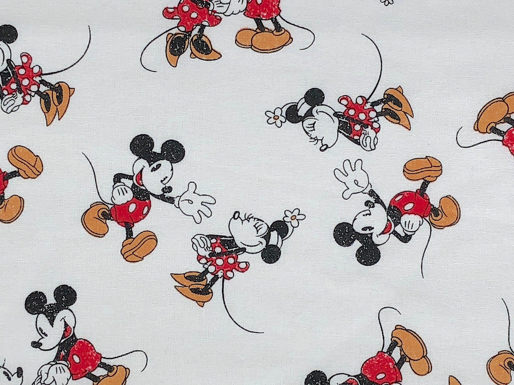 Mickey and Minnie Mouse on white cotton fabric.