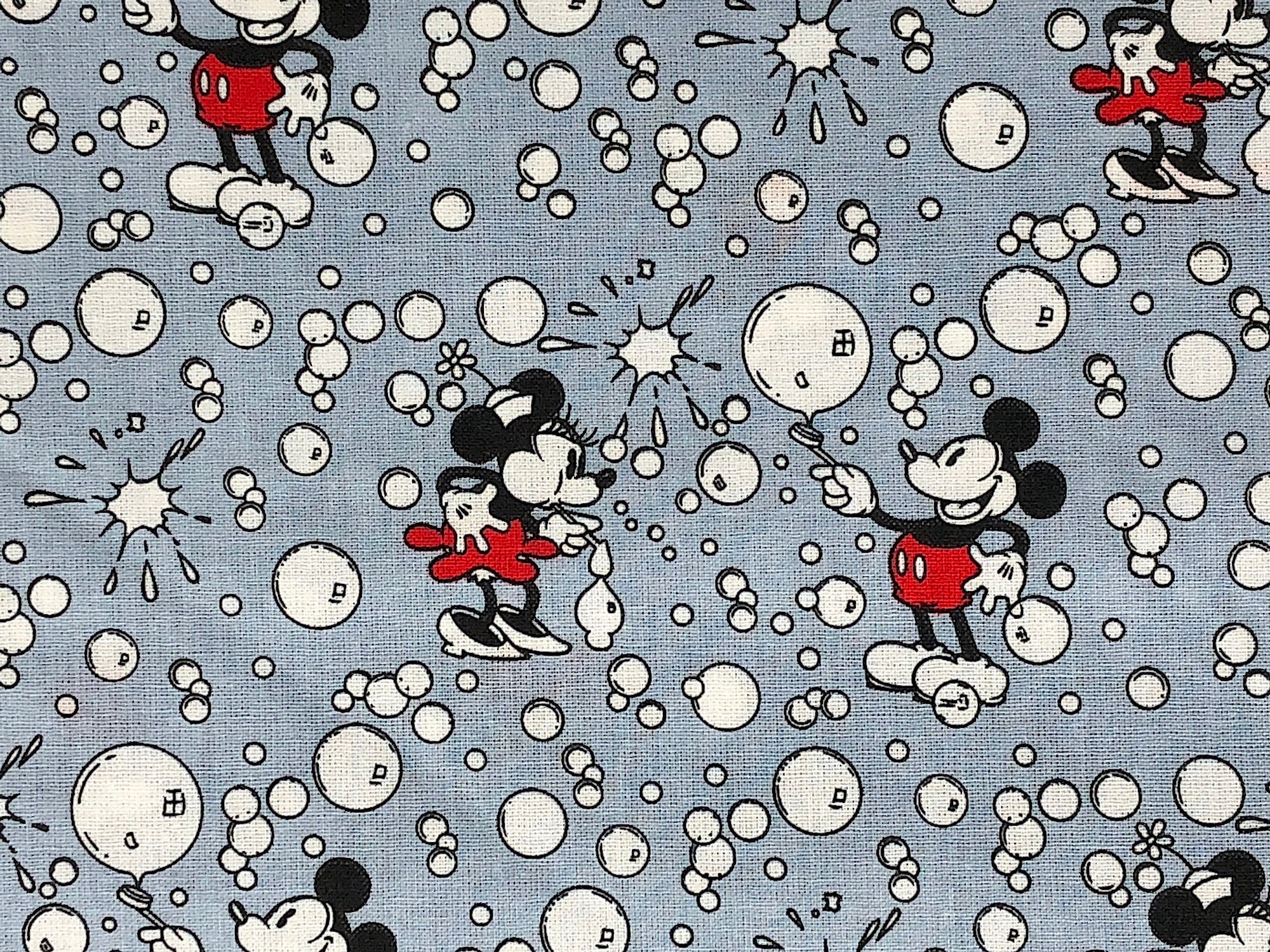Close up of Mickey and Minnie Mouse blowing bubbles on a grey background.