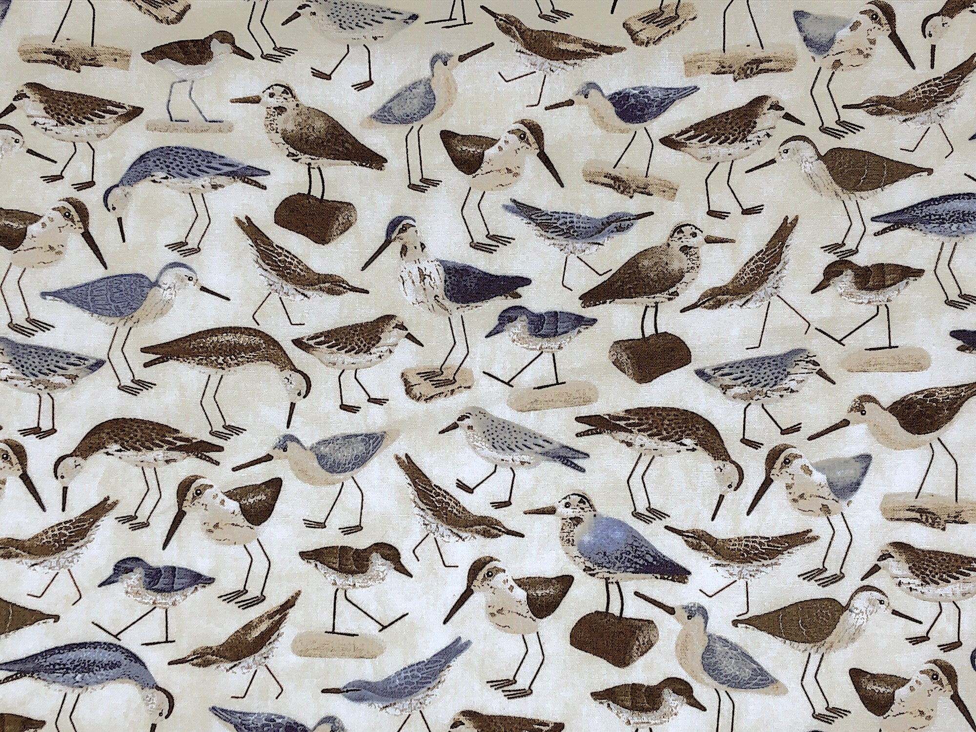 This nautical fabric is called Water Birds and is covered with birds. Some of the birds are standing on sand and others are standing on driftwood.