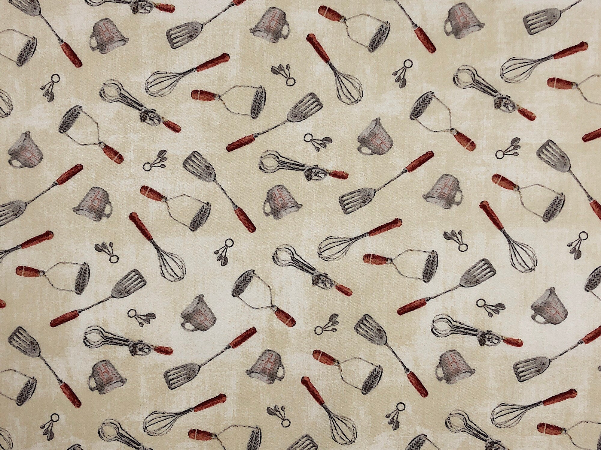 This fabric is called Homemade Happiness and is covered with kitchen utensils such as measuring cups, spatulas, measuring spoons, potato masher whip and more. The background is light cream and a very light beige