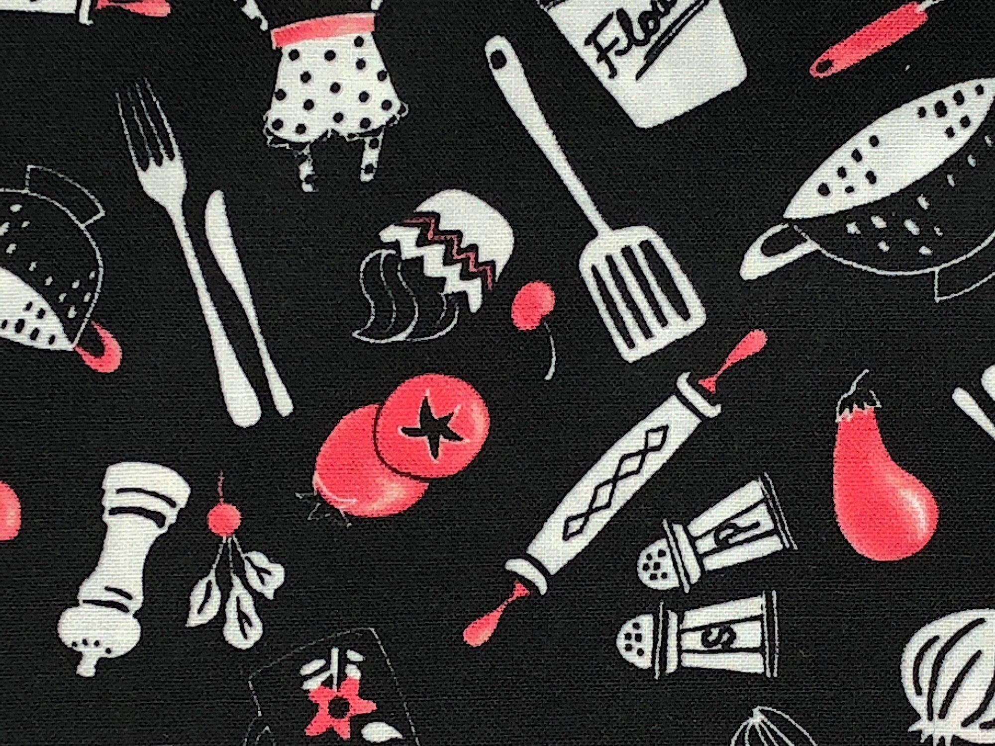 Black cotton fabric covered with tomatoes, chili peppers, colanders and more.