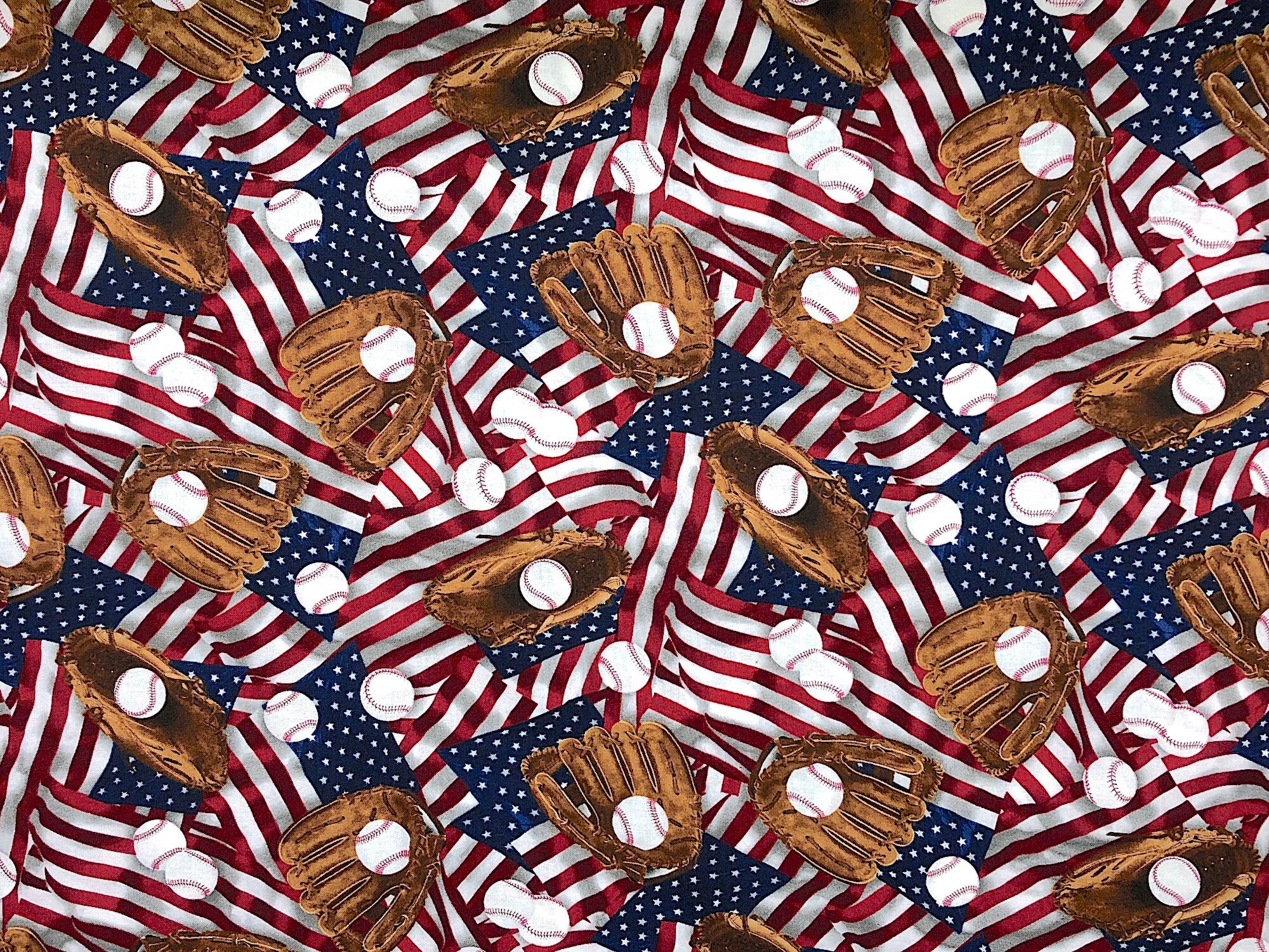 Cotton fabric covered with USA flags, baseball mitts and balls.
