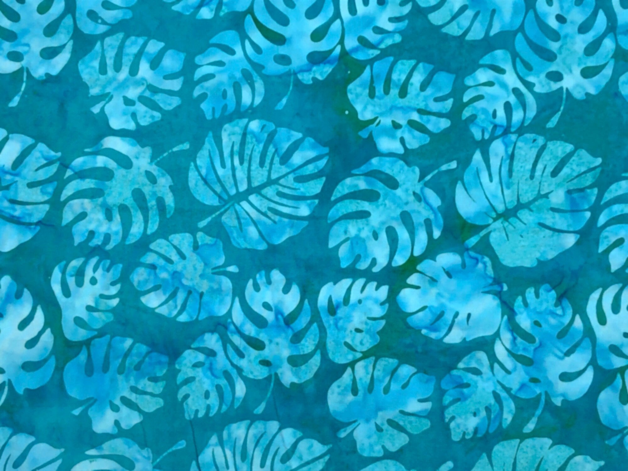 This fabric is called Philodendron Teal and is covered with leaves.