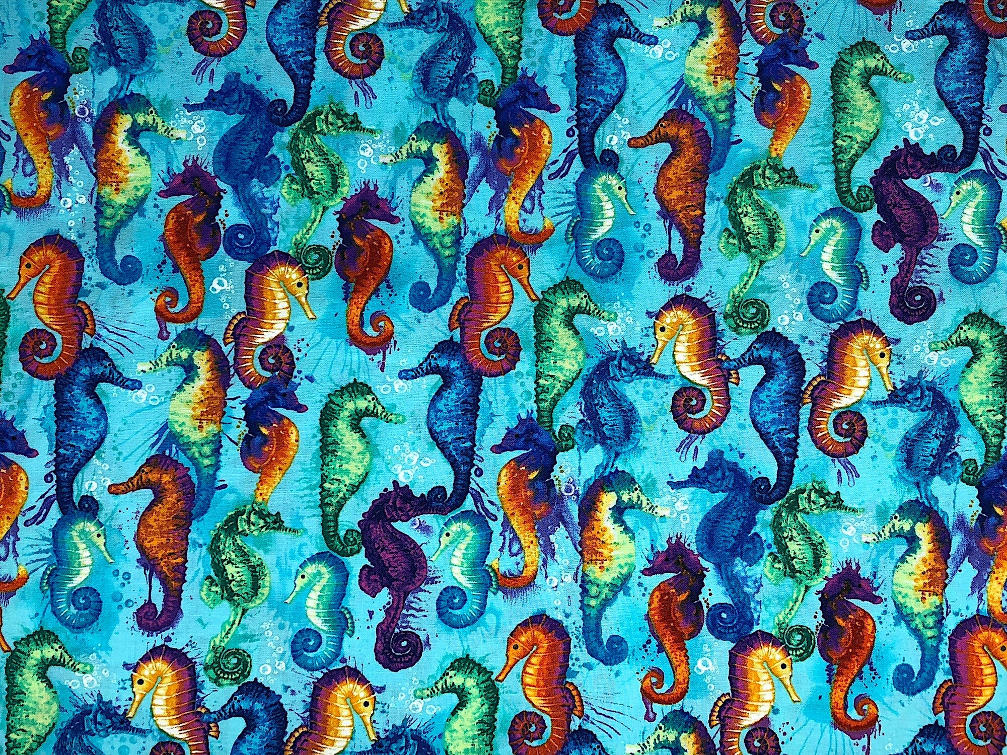 Swimming Seahorses cover this fabric. The seahorses are blue, green, yellow, orange and purple. the background is a pretty turquoise blue