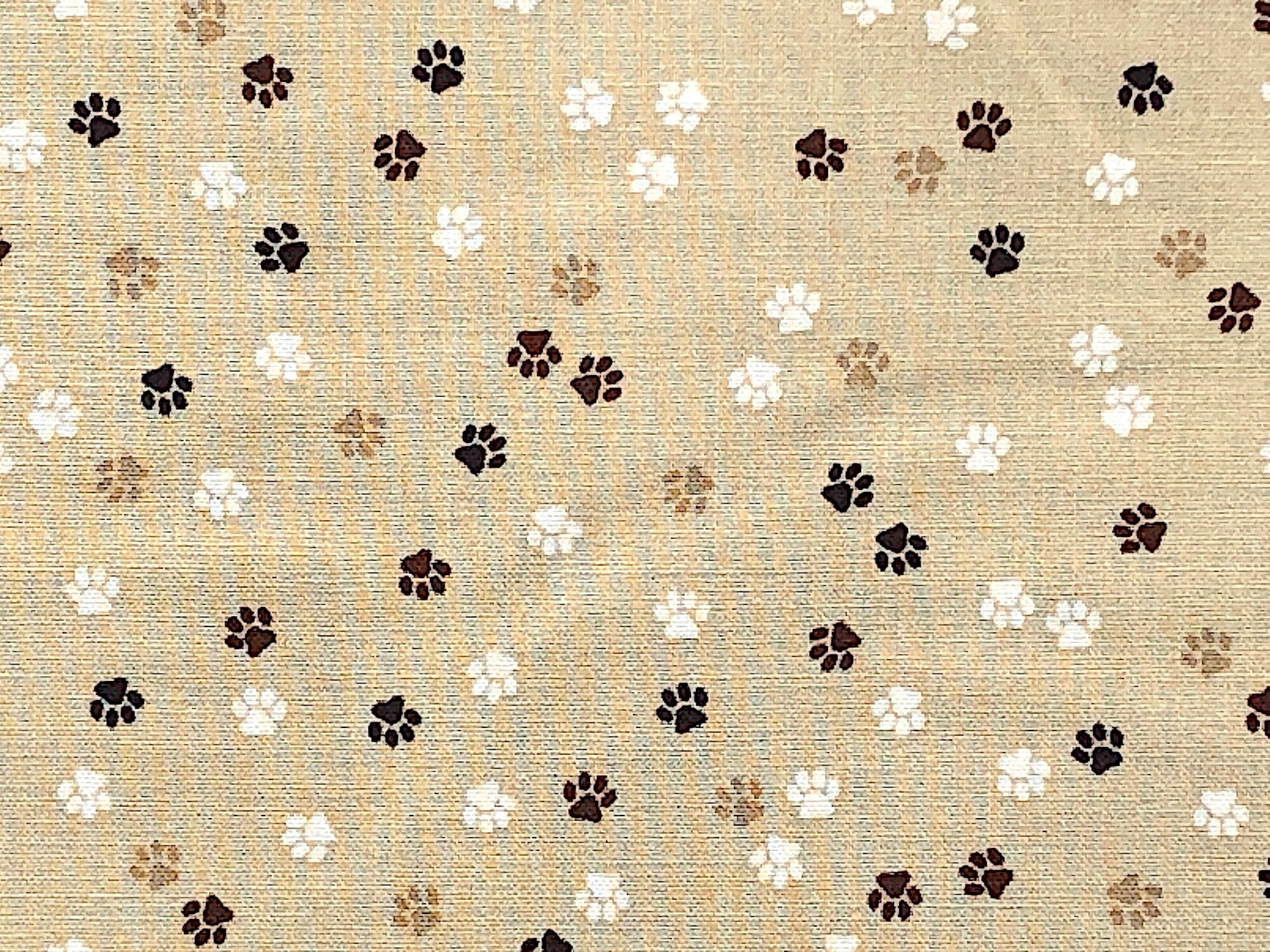Brown and Cream colored Paw Prints cover this beige fabric