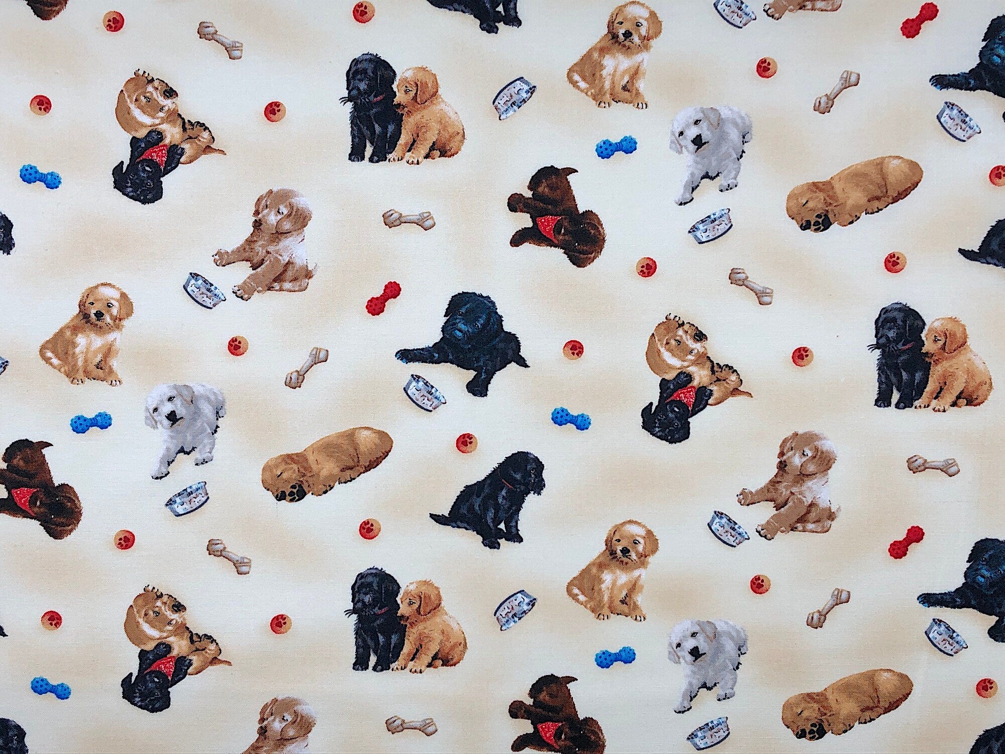 This fabric is covered with black, white and beige puppies. The background is a mix of cream and beige.