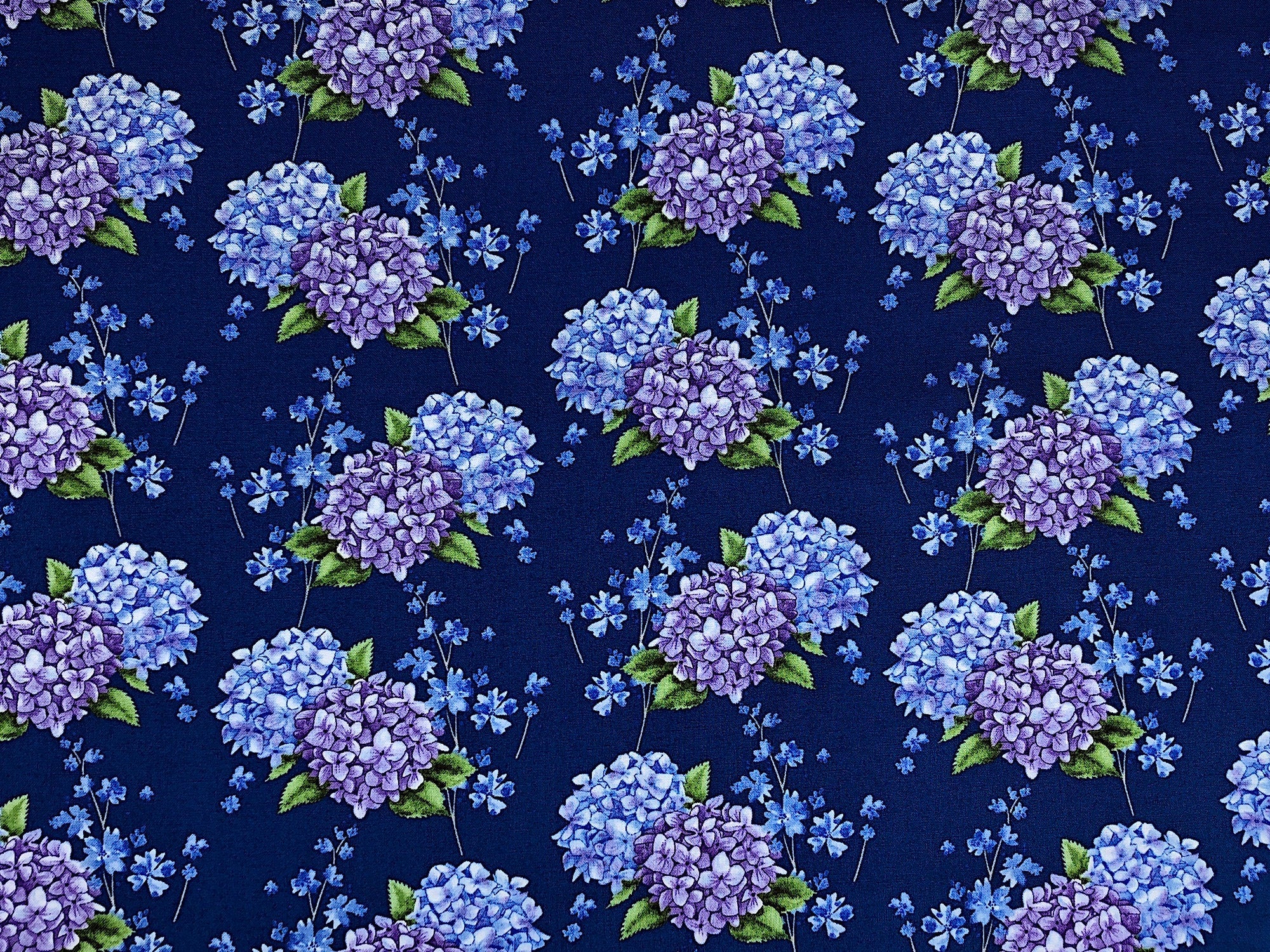 Blue cotton fabric covered with blue and purply hydrangeas.