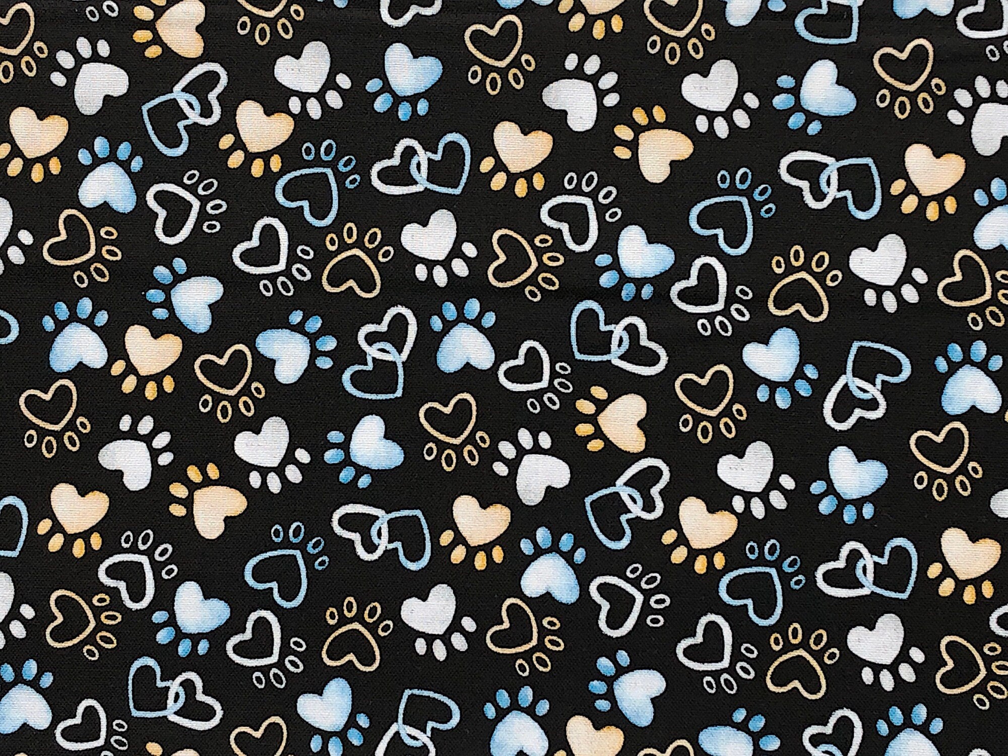 Close up of paw prints and hearts on a black background.