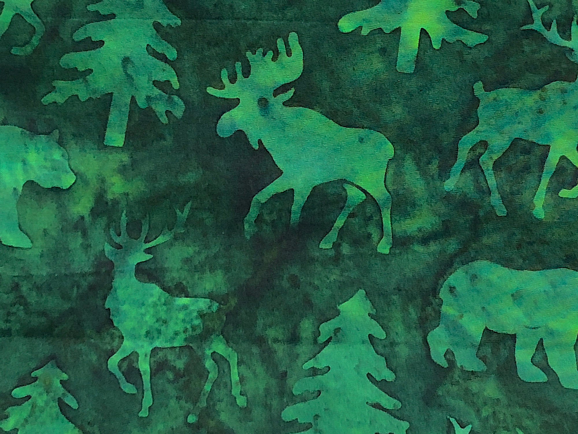 Close up of green batik fabric with elk, deer, trees and bears.