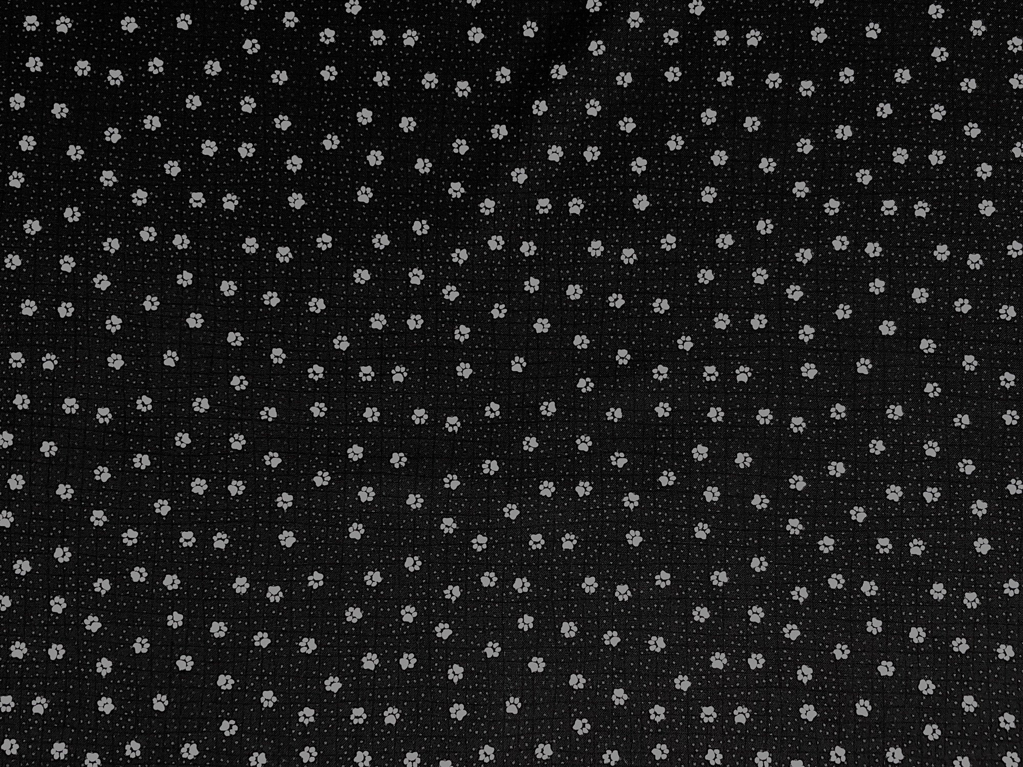 This black cotton fabric is covered with white paw prints
